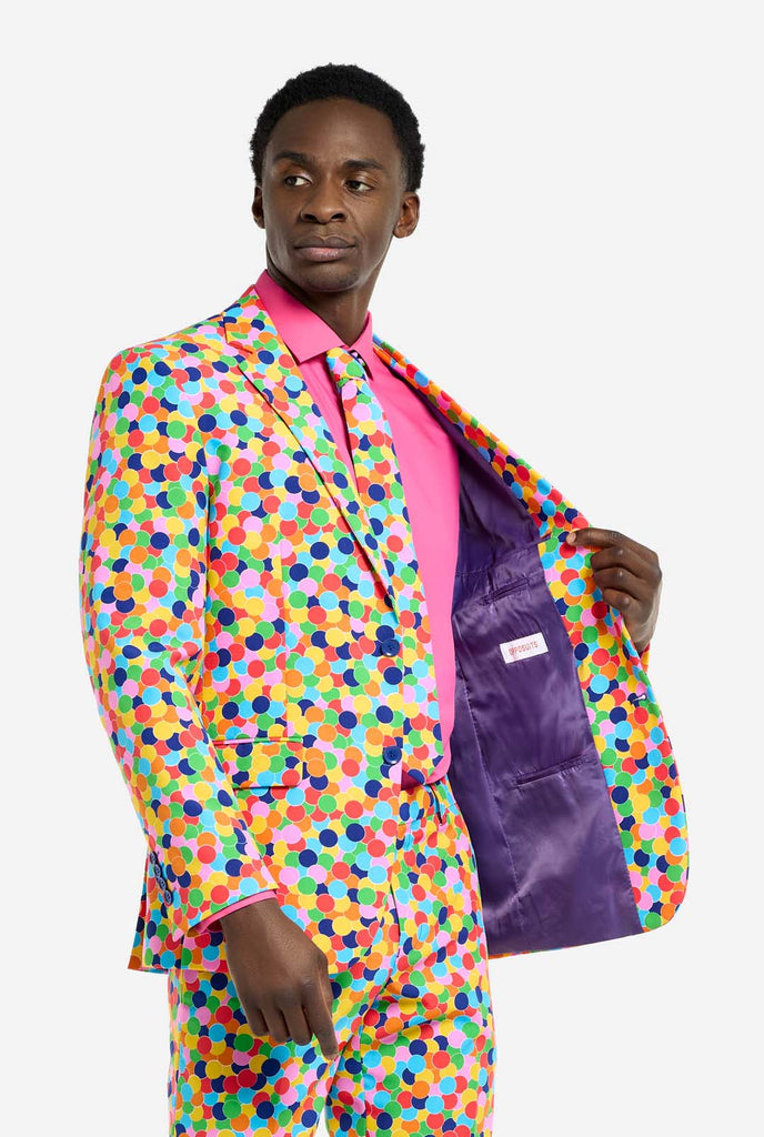 Image of a man wearing an OppoSuits Confetteroni men's suit with confetti print and pink men's shirt. Suit consist of pants, jacket and tie.