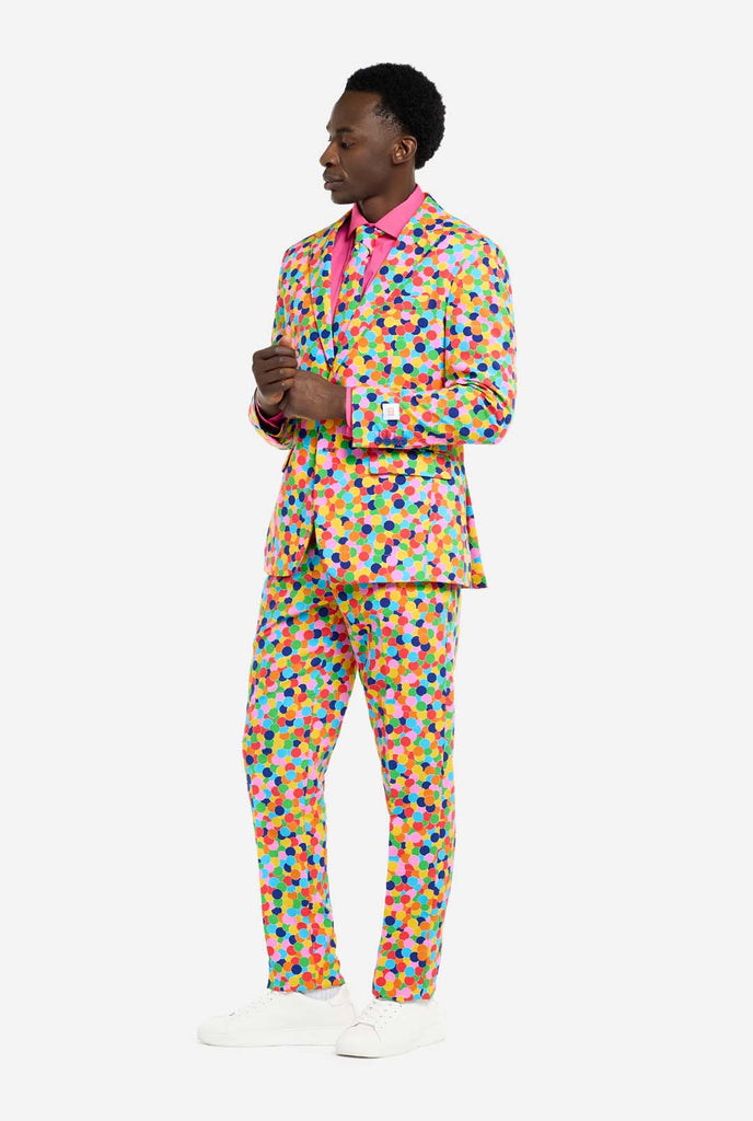 Image of a man wearing an OppoSuits Confetteroni men's suit with confetti print and pink men's shirt. Suit consist of pants, jacket and tie.