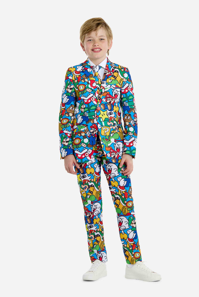 Image of teen wearing a Super Mario all over print shirt, consisting of blazer, pants and tie. Main color is blue, but there is also yellow, red and white.