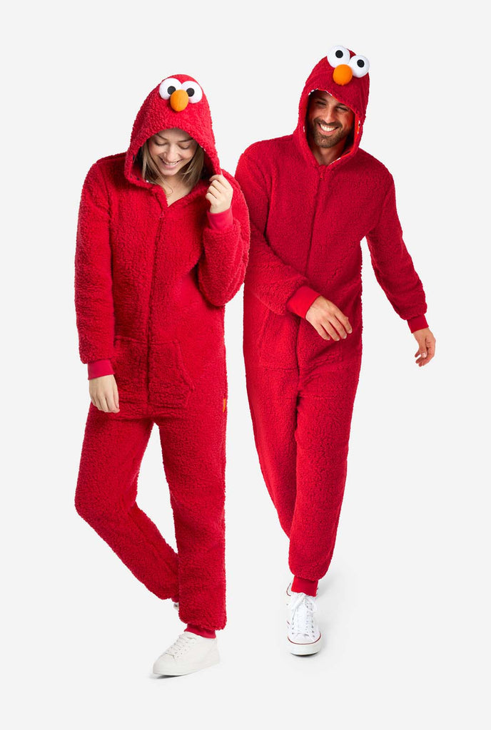 A man and a woman are dressed in a red Elmo-themed onesie. The overall design mimics the look of the Sesame Street character Elmo. The background is plain, putting focus on the costume. Full body image.