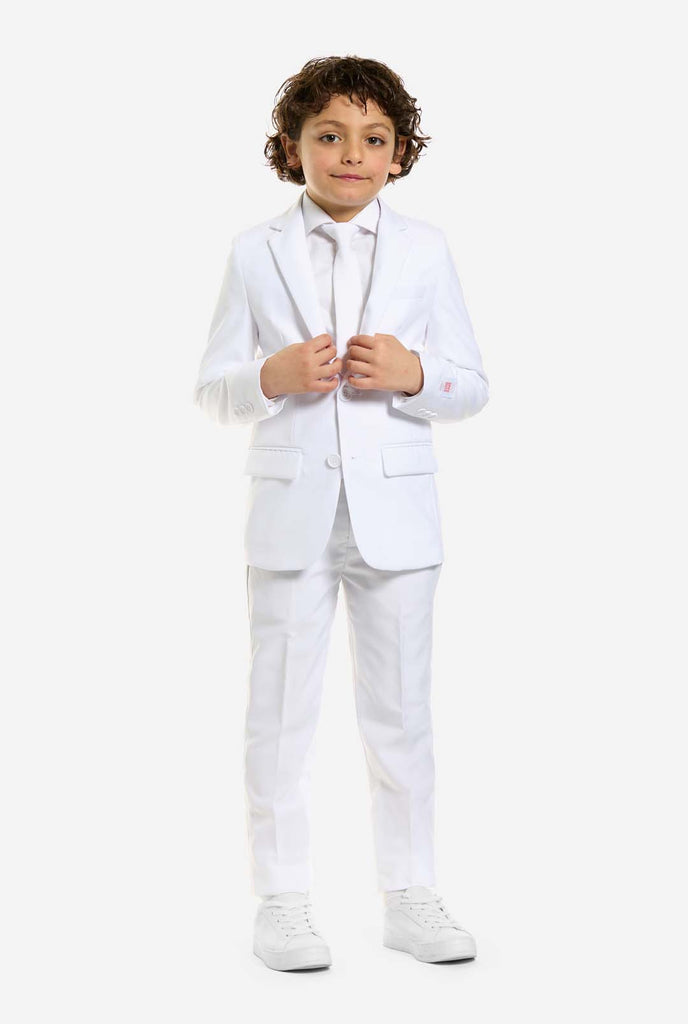 In this image, a kid is wearing a white suit for boys and white shirt. The consists of jacket, pants and clip-on tie.