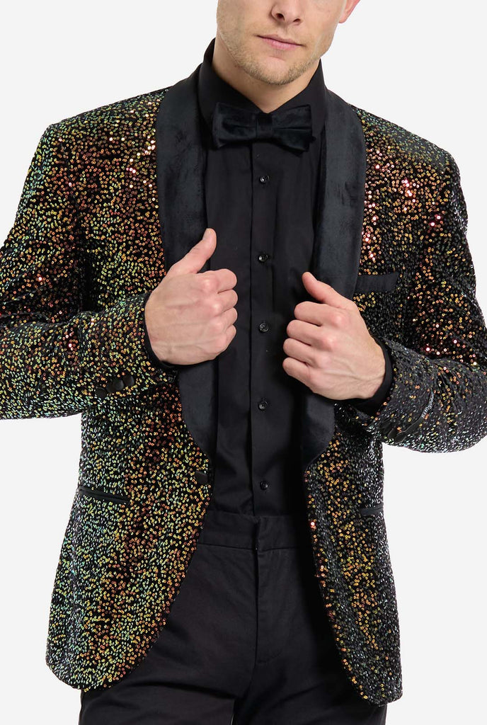 Man wearing blazer covered in with shimmering amber-colored sequins that reflect light in various shades of gold, copper, and green. Close up. 