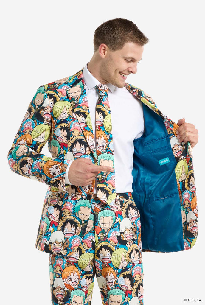 Man is wearing a men's suit with all over One piece print with One Piece characters. Holding one side of the jacket open.