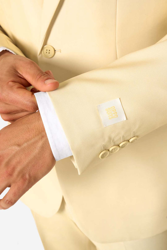 Elegant men's suit in a soft pastel yellow shade, perfect for weddings, summer events, and formal occasions. This stylish tailored suit features a slim fit design, notch lapels, and a matching tie for a sophisticated look. Ideal for modern gentlemen looking to make a statement with a light-colored pastel suit. Sleeve close-up.