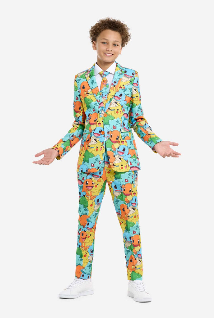 Teen wearing formal multi color suit with all-over Pokemon print. The suit contains the characters Pikachu, Bulbasaur, Charmander and Squirtle.