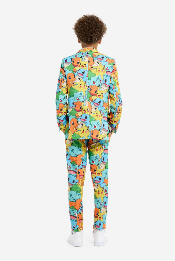 Teen wearing formal multi color suit with all-over Pokemon print. The suit contains the characters Pikachu, Bulbasaur, Charmander and Squirtle.