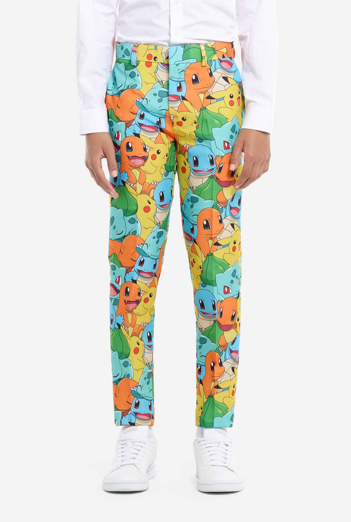 Teen wearing formal multi color suit with all-over Pokemon print. The suit contains the characters Pikachu, Bulbasaur, Charmander and Squirtle.