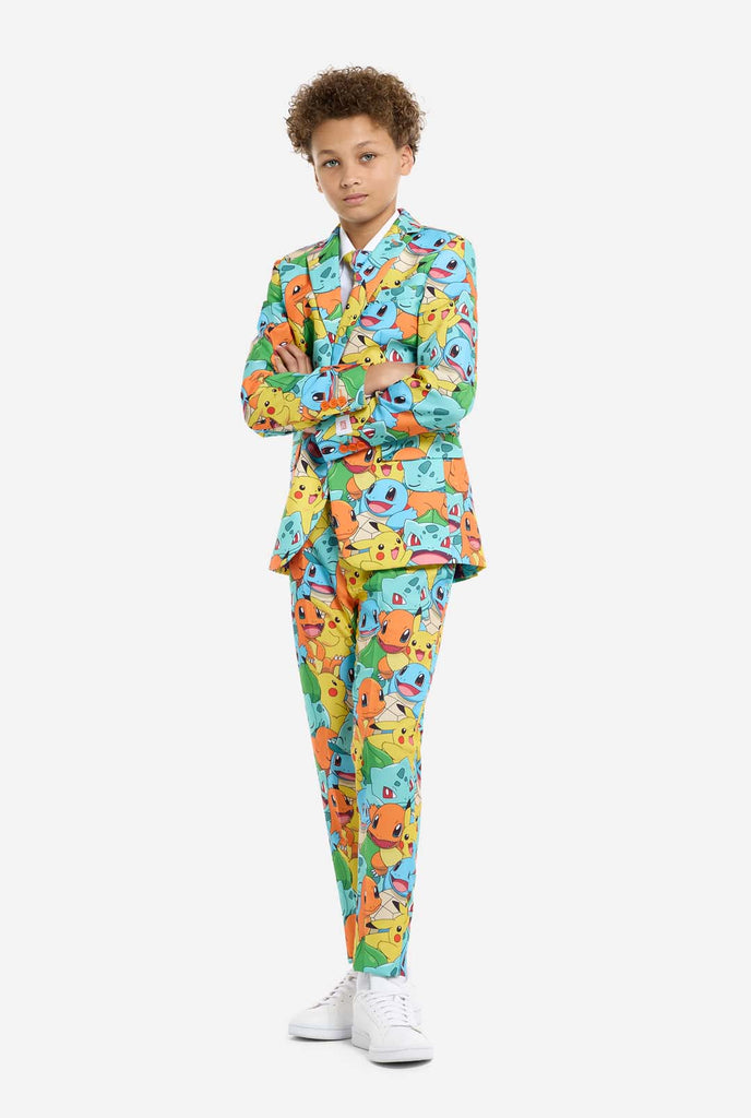 Teen wearing formal multi color suit with all-over Pokemon print. The suit contains the characters Pikachu, Bulbasaur, Charmander and Squirtle.