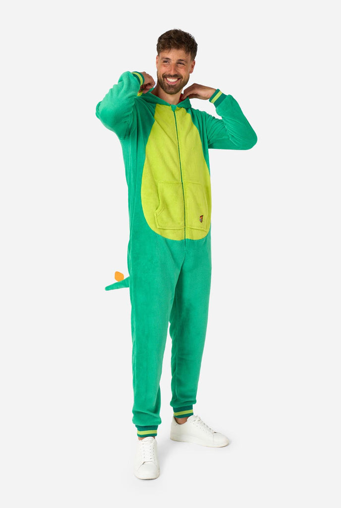 A man is wearing a green dinosaur adult onesie featuring playful hood details and cozy, soft material, perfect for lounging or costume events. Full body image with the hood own on his back.