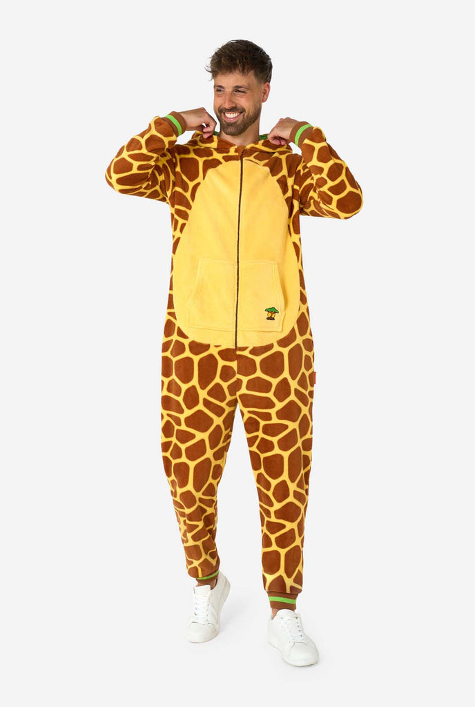 A smiling man is wearing a brown and yellow adult onesie designed as a giraffe. The onesie features a hood resembling a Giraffes head, and giraffe details, perfect for cozy lounging or costume parties. Full body image with the hood down.