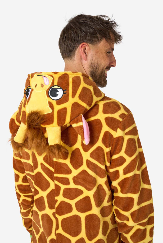 A smiling man is wearing a brown and yellow adult onesie designed as a giraffe. The onesie features a hood resembling a Giraffes head, and giraffe details, perfect for cozy lounging or costume parties. Upper body close-up showing the back.