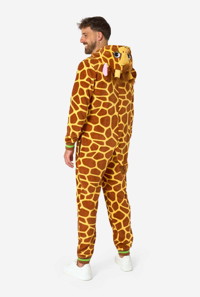 A smiling man is wearing a brown and yellow adult onesie designed as a giraffe. The onesie features a hood resembling a Giraffes head, and giraffe details, perfect for cozy lounging or costume parties. Full body image showing the side.