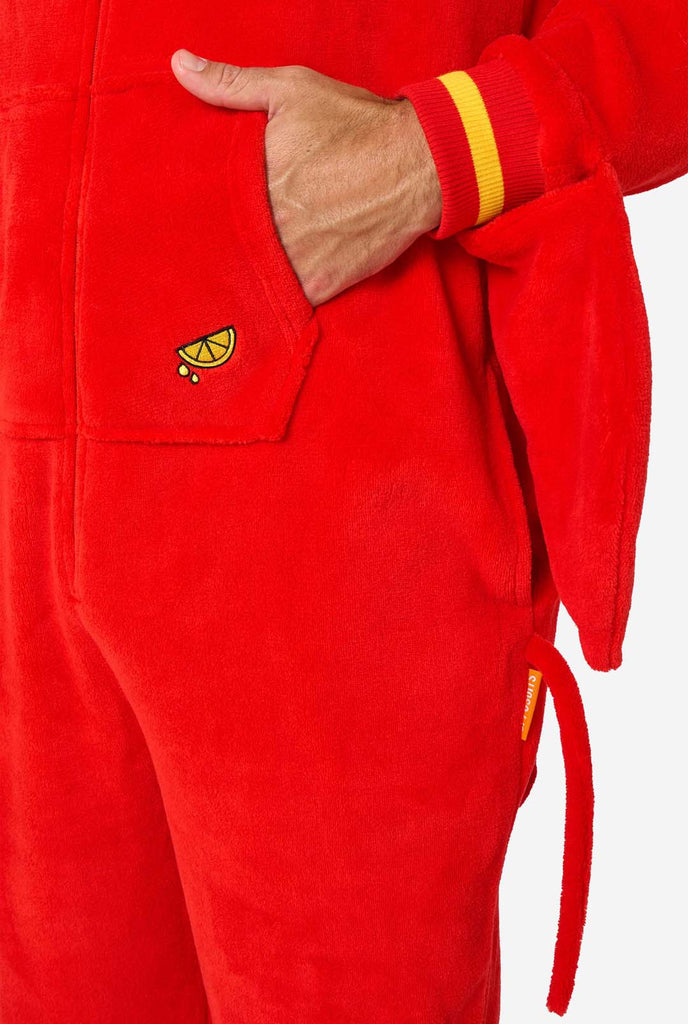 A man is wearing a bright red lobster-themed adult onesie featuring playful hood details and cozy, soft material, perfect for lounging or costume events. including stitched gloves as claws. Pocket close-up.