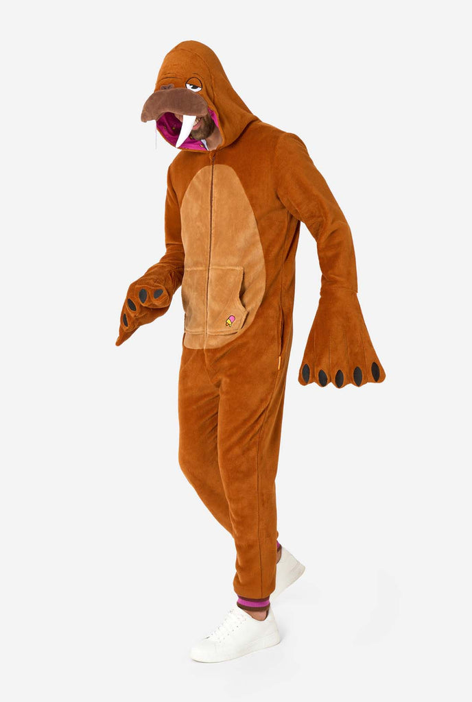 A cheerful man wearing a brown adult onesie designed as a walrus. The onesie features a hood with fangs, stitched gloves resembling paws, and playful walrus details, perfect for cozy lounging or costume parties. Full body image.