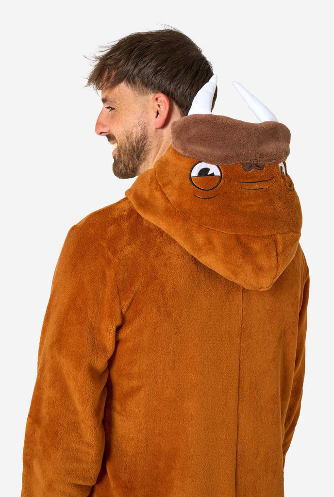 A cheerful man wearing a brown adult onesie designed as a walrus. The onesie features a hood with fangs, stitched gloves resembling paws, and playful walrus details, perfect for cozy lounging or costume parties. Upper body close up, hood is down on his back.