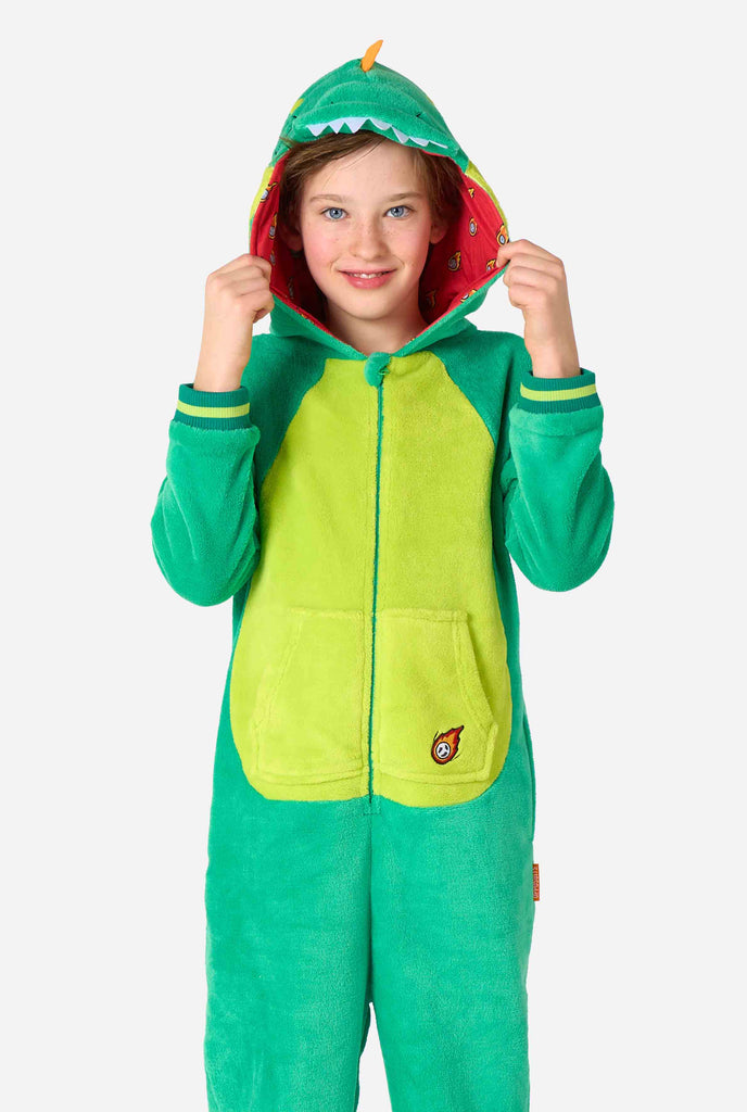 A kid is wearing a green dinosaur kids onesie featuring playful hood details and cozy, soft material, perfect for lounging or costume events. 