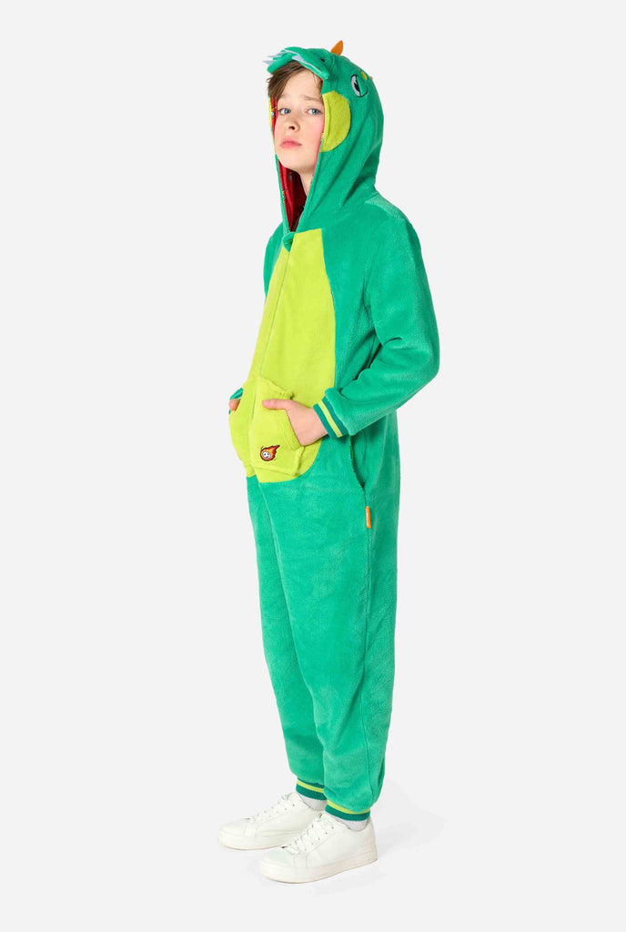 A kid is wearing a green dinosaur kids onesie featuring playful hood details and cozy, soft material, perfect for lounging or costume events. Full body image.