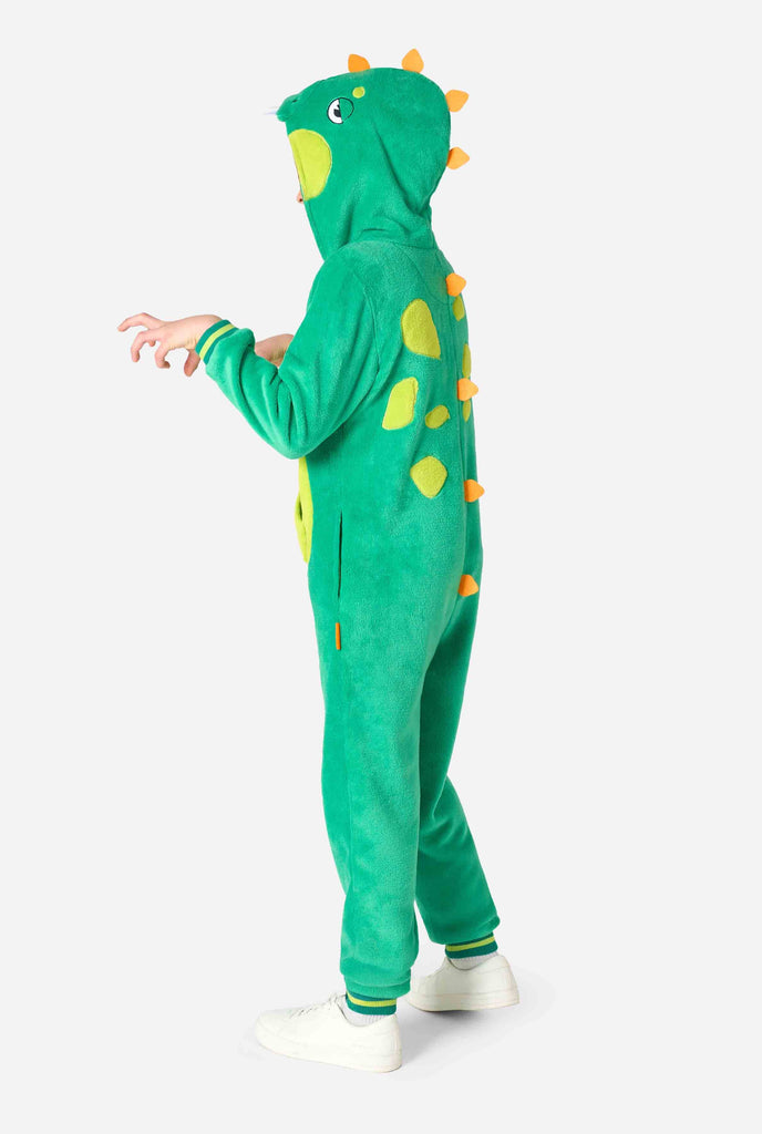 A kid is wearing a green dinosaur kids onesie featuring playful hood details and cozy, soft material, perfect for lounging or costume events. Side view.