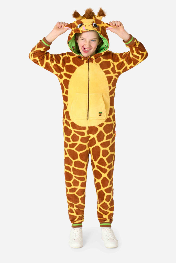 A smiling kid is wearing a brown and yellow kids onesie designed as a giraffe. The onesie features a hood resembling a Giraffes head. Full body image.