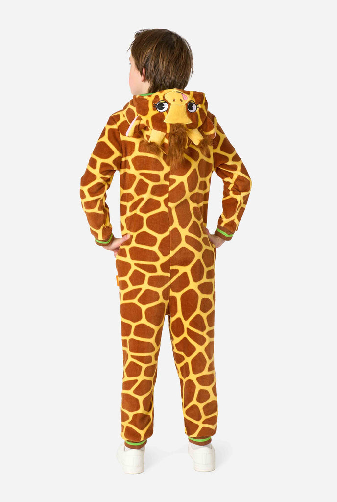 A smiling kid is wearing a brown and yellow kids onesie designed as a giraffe. The onesie features a hood resembling a Giraffes head. View from the back.