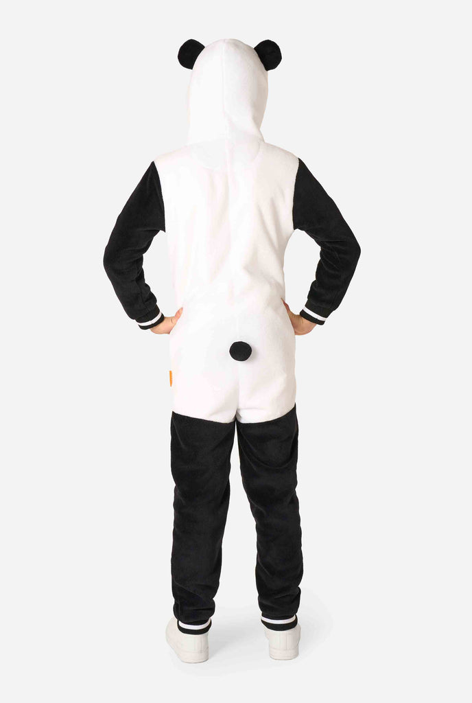 A smiling kid wearing a panda-themed kids onesie. This cozy onesie features black and white panda colors with a playful hood showcasing panda ears and a cute face. Perfect for lounging or fun costume occasions. View from the back.