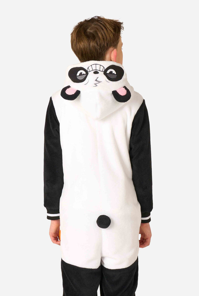 A smiling kid wearing a panda-themed kids onesie. This cozy onesie features black and white panda colors with a playful hood showcasing panda ears and a cute face. Perfect for lounging or fun costume occasions. View from the back, with the hood down.