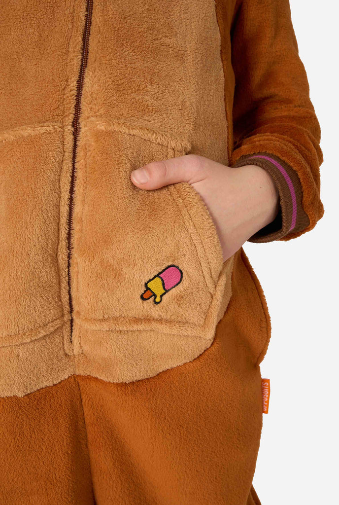 A cheerful kid wearing a brown kids onesie designed as a walrus. The onesie features a hood with fangs, stitched gloves resembling paws, and playful walrus details, perfect for cozy lounging or costume parties. Close up.