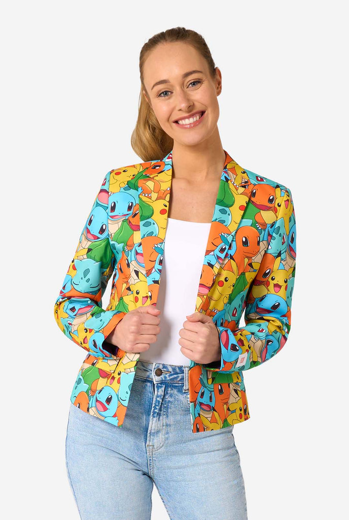 Smiling woman wearing a colorful Pokémon-themed women's blazer featuring characters like Pikachu, Squirtle, and Charmander, styled with a white top and light-wash jeans.