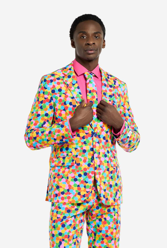 Video of a man wearing an OppoSuits Confetteroni men's suit with confetti print and pink men's shirt. Suit consist of pants, jacket and tie.